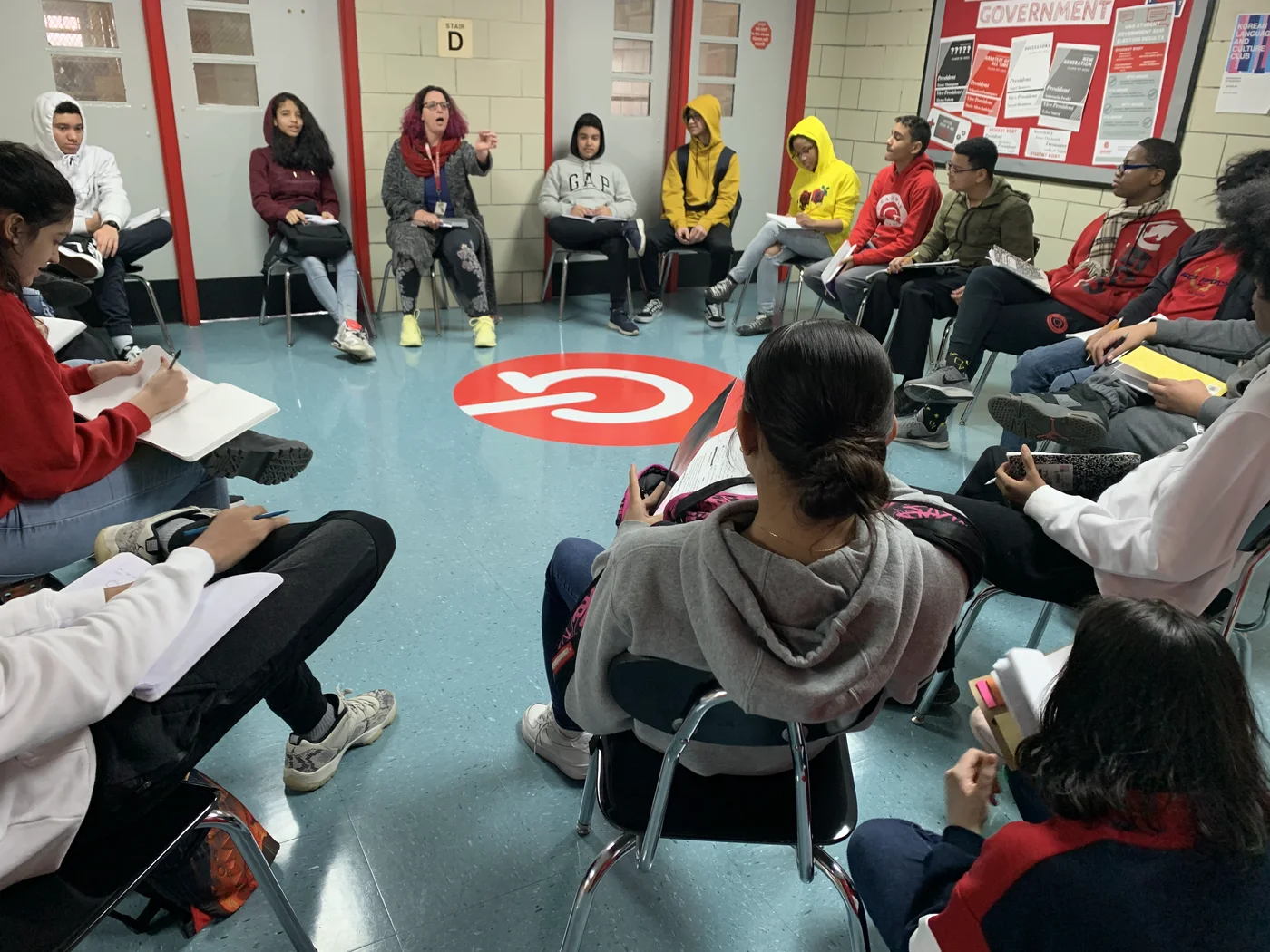 Students and an educator seated in a circle for a school discussion